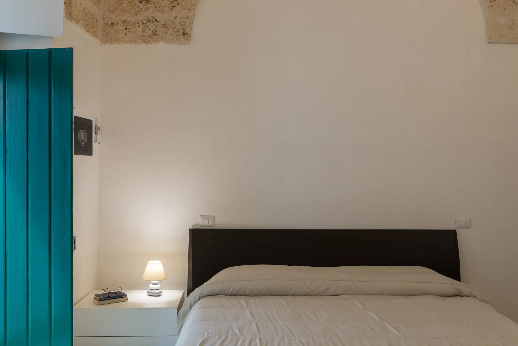 A bedroom with a neatly made bed beside a small bedside table.