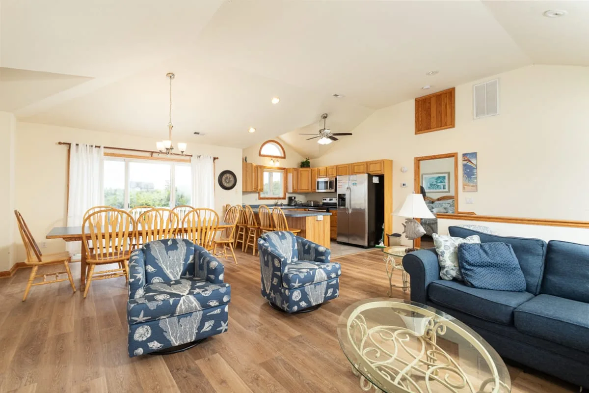 Sala de estar y cocina de concepto abierto con asientos azules y comedor.