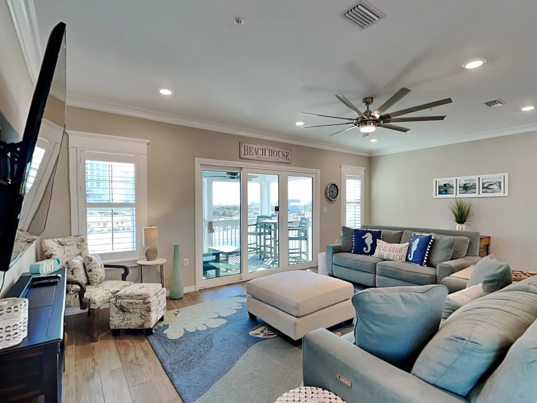 A living room with seating around a coffee table and glass doors opening to a balcony.