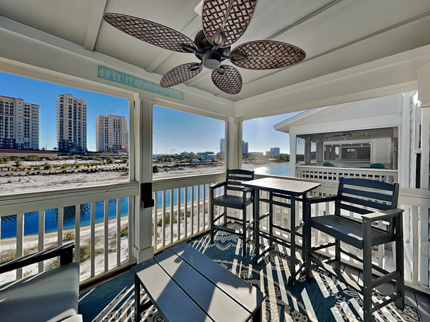 A covered balcony has outdoor seating and views of the water and nearby buildings.