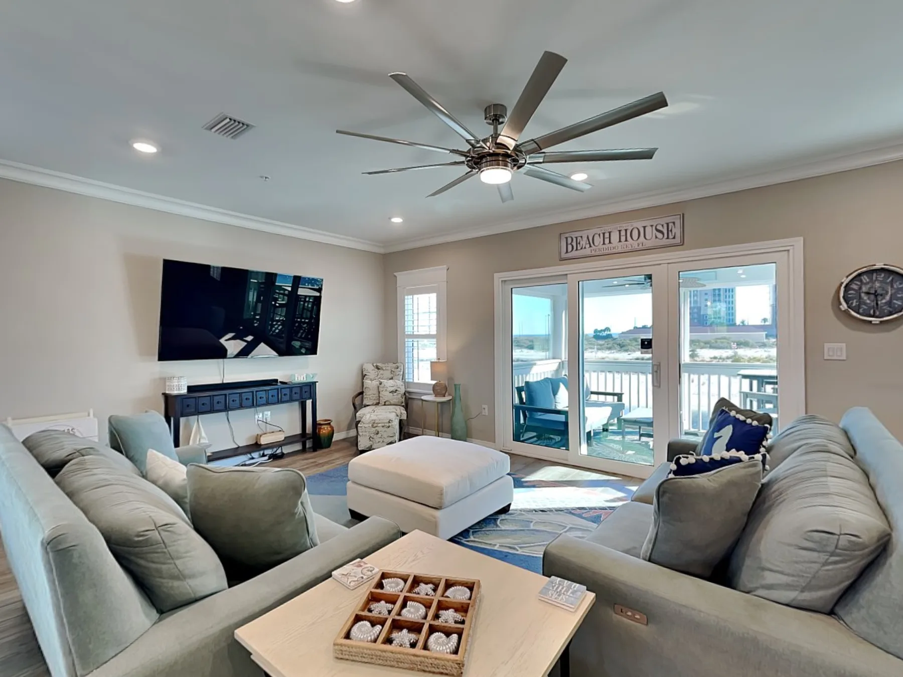 A bright living room with seating, a coffee table, and glass doors opening to a balcony.