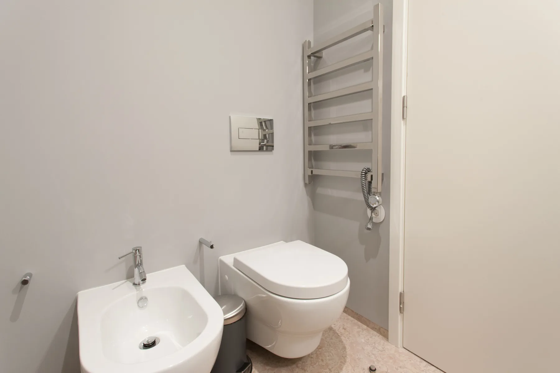 Un baño con lavabo, inodoro y toallero calefactable en la pared.