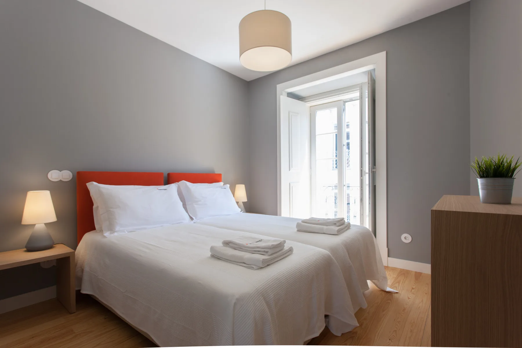 A bright bedroom with a neatly made bed and a large window.