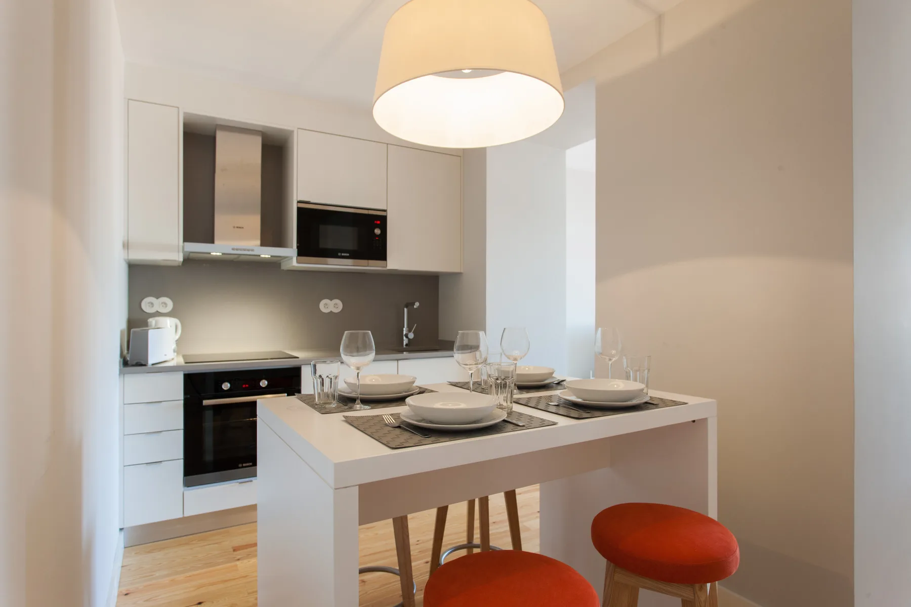 Una cocina moderna con una mesa de comedor puesta con platos y vasos.
