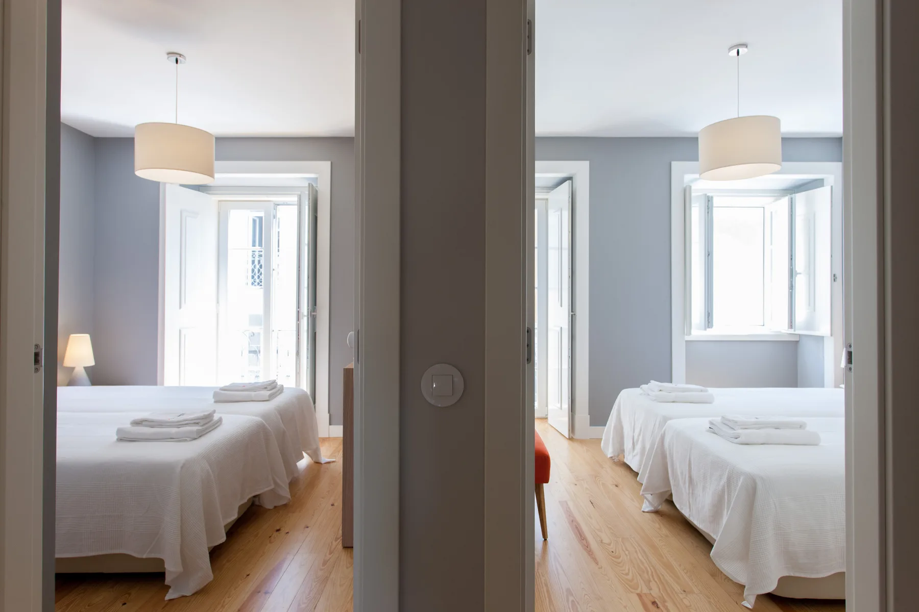 Dormitorio con ropa de cama blanca, lámparas colgantes y ventanas altas.