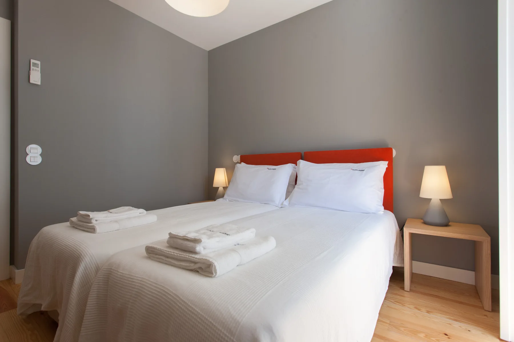 Un dormitorio con una cama doble, ropa de cama blanca y lámparas de noche.