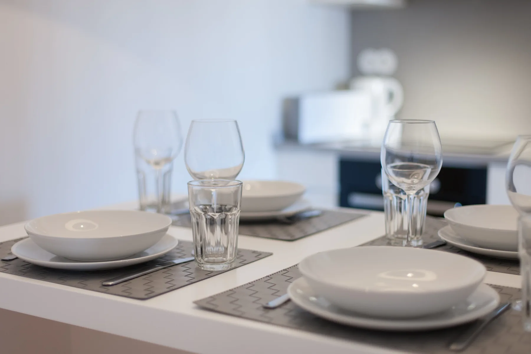 Una mesa de comedor está puesta con platos, vasos y cubiertos.