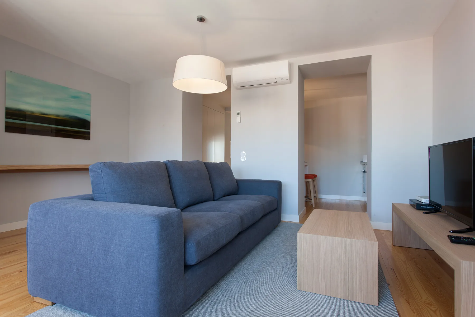 A living room with blue seating, a coffee table, and a television.