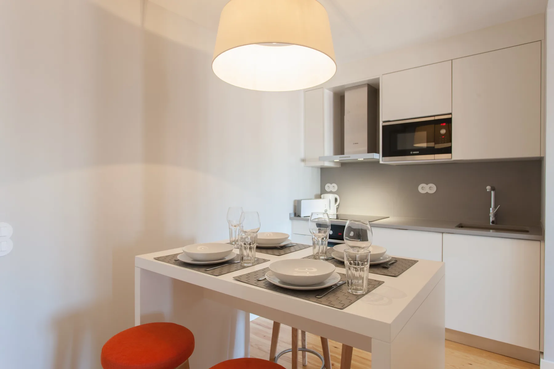 A compact kitchen and dining area with a table set beneath a pendant light.