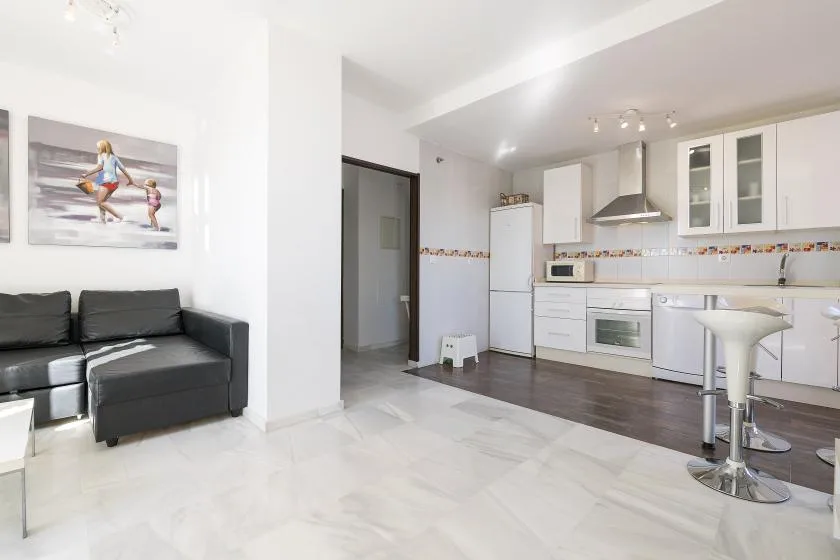 An open-plan kitchen and living area with white cabinets and dark seating.