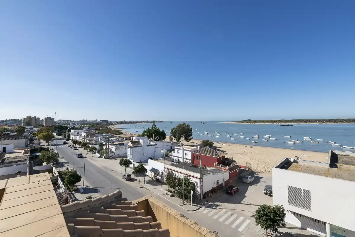 Aerial view of a coastal town beside a bay with boats and a sandy beach.