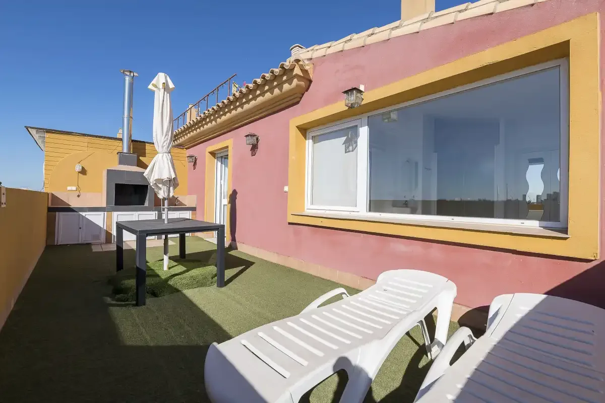 A sunny rooftop terrace with lounge seating and a large window.
