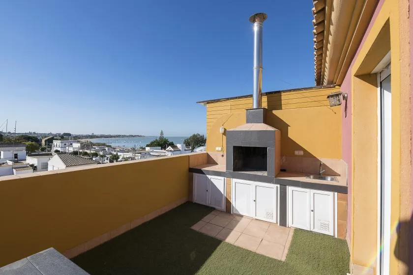 A rooftop terrace features a built-in barbecue and a view of the water.