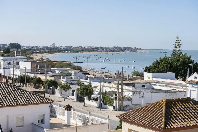 Coastal town and bay seen above nearby rooftops, with boats scattered across the water.