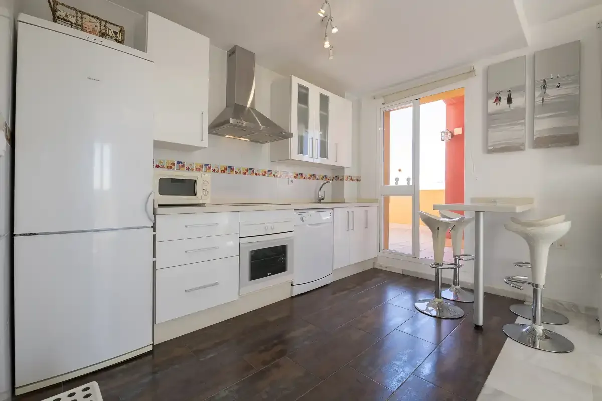 A bright kitchen with white cabinets, appliances, and a small breakfast bar.