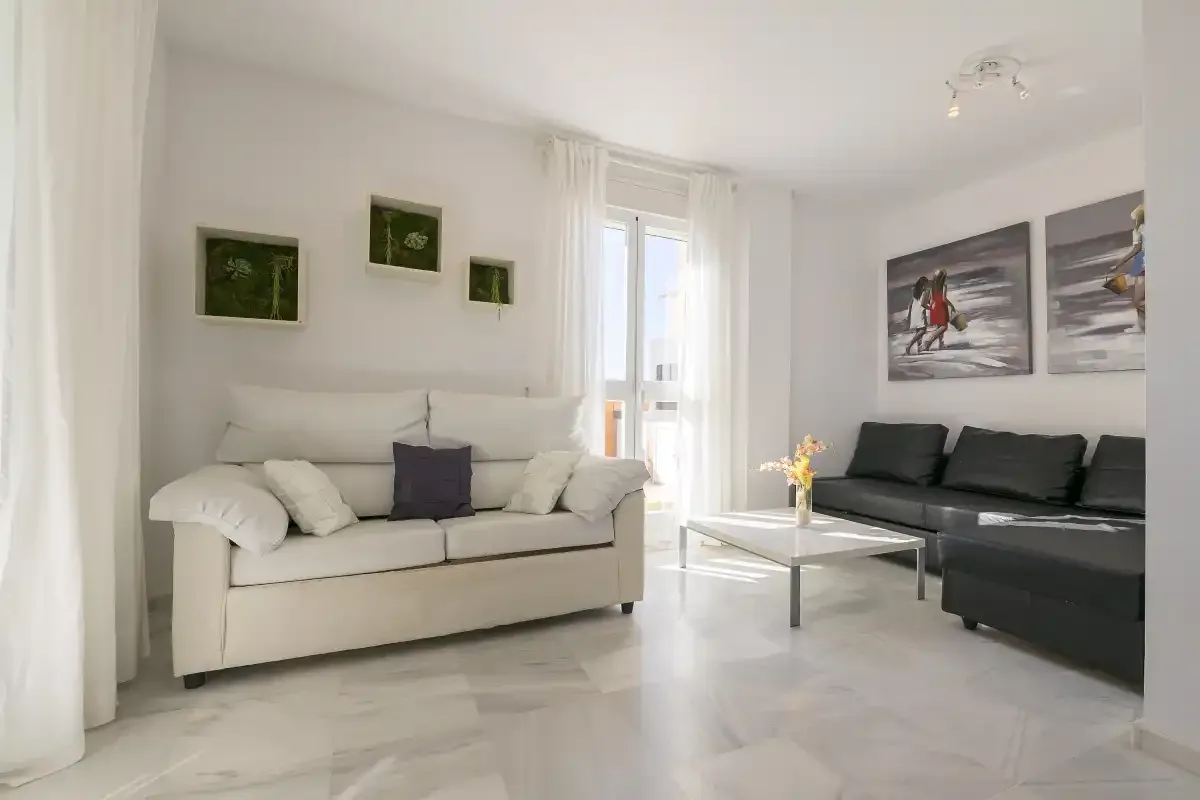 Living room with light seating, a dark sectional, and a glass coffee table.