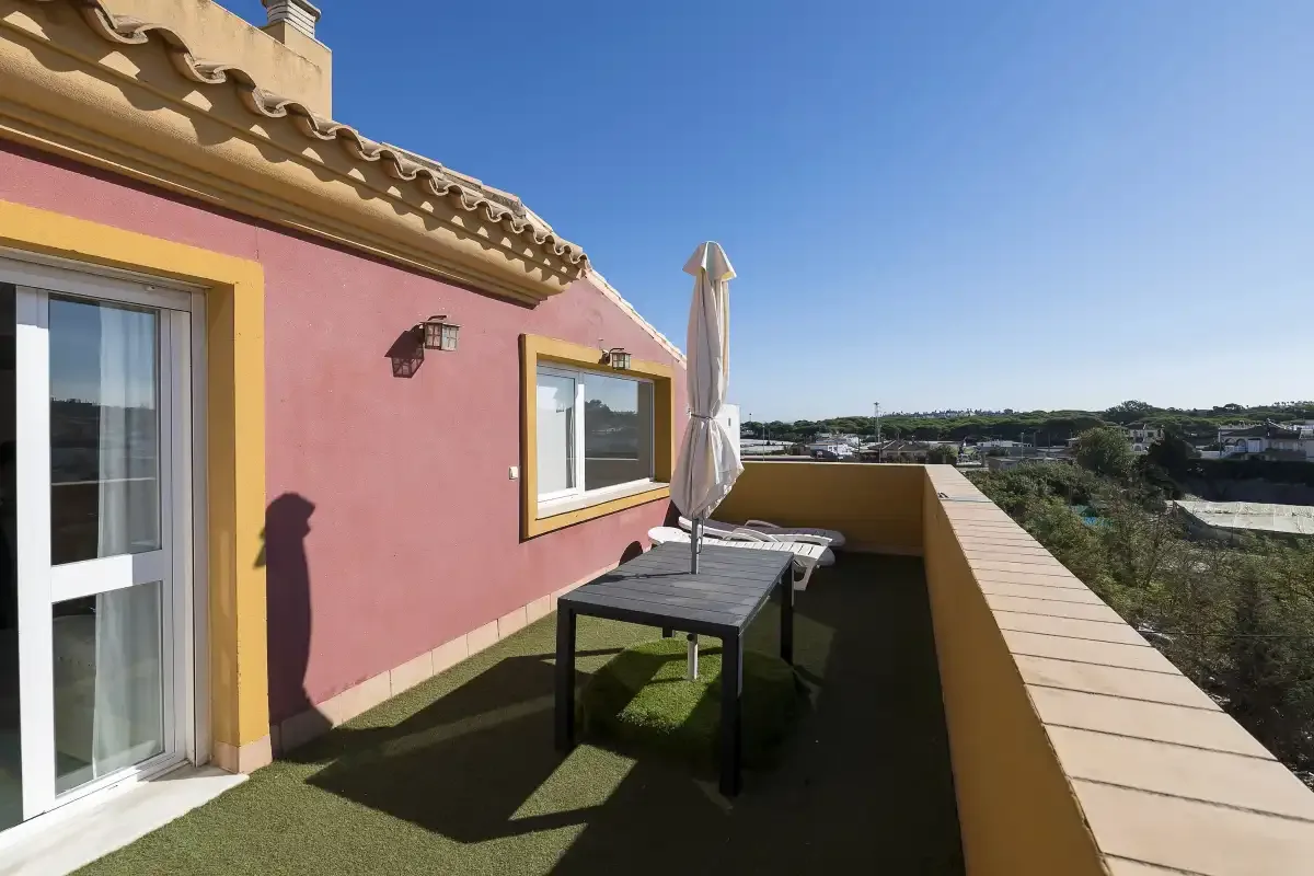 A rooftop terrace with outdoor seating and a closed umbrella.