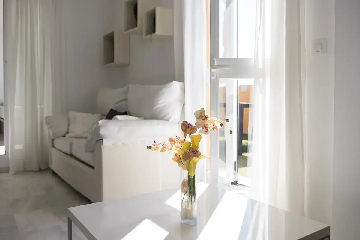 A bright living room with white seating and flowers on a table.
