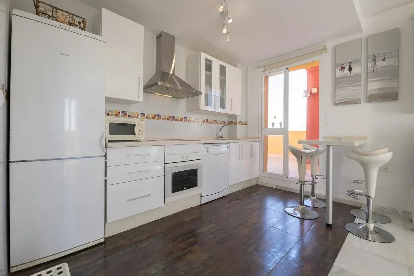 A bright kitchen with white cabinets and a small counter-height dining area.