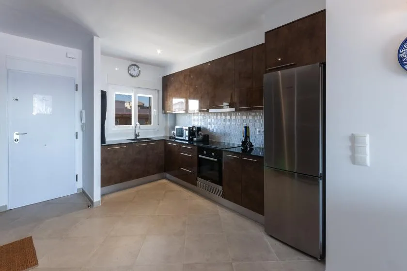 A modern kitchen with dark cabinets, stainless steel appliances, and a tiled backsplash.
