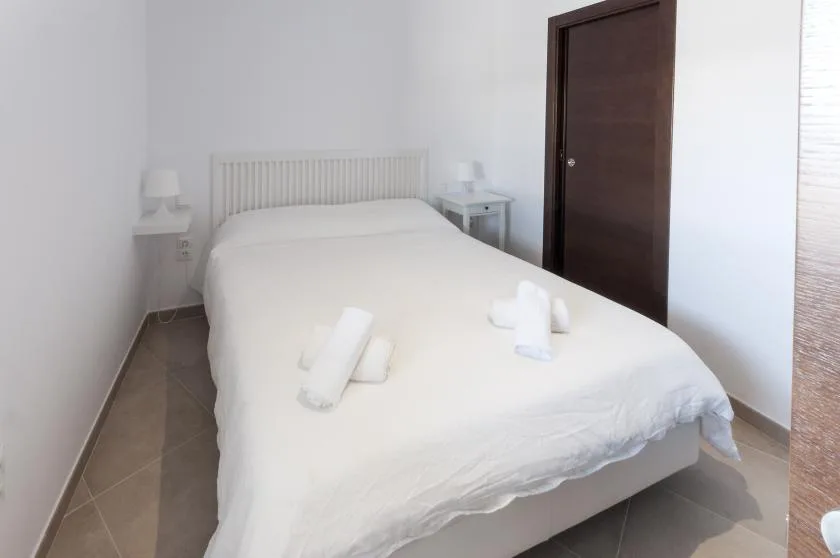 A bright bedroom with a white bed and bedside tables.