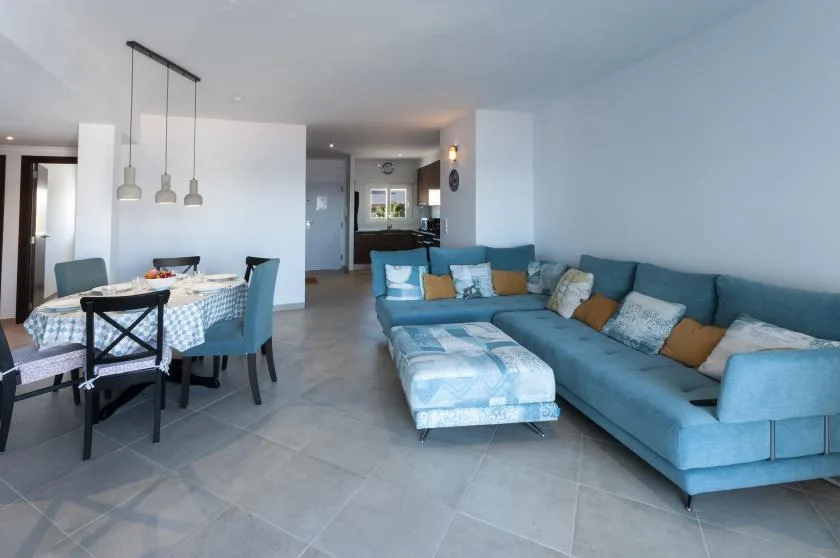 A bright living and dining area with a blue sectional and a round dining table.