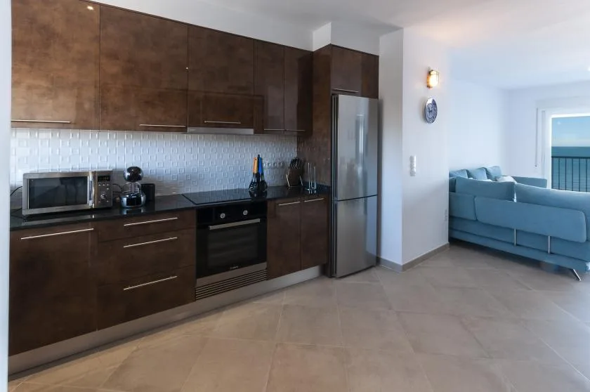 A modern kitchen opens onto a living area with blue seating.