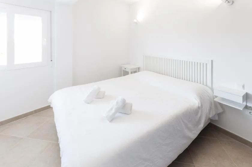 A bright bedroom with a large bed and white bedding.