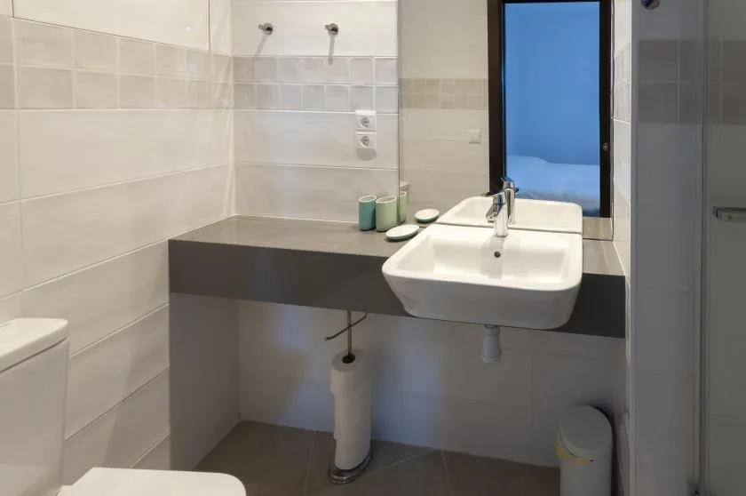 A tiled bathroom has a white sink set into a dark vanity.