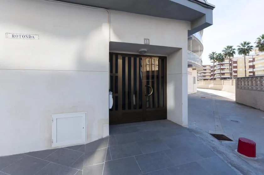 A building entrance with a dark barred door opens onto a paved outdoor walkway.