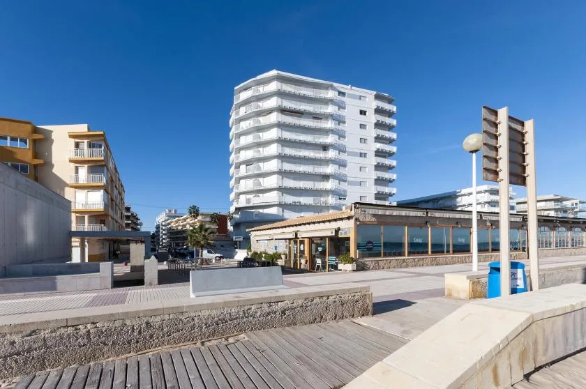 A paved public plaza sits among modern buildings beneath a clear blue sky.