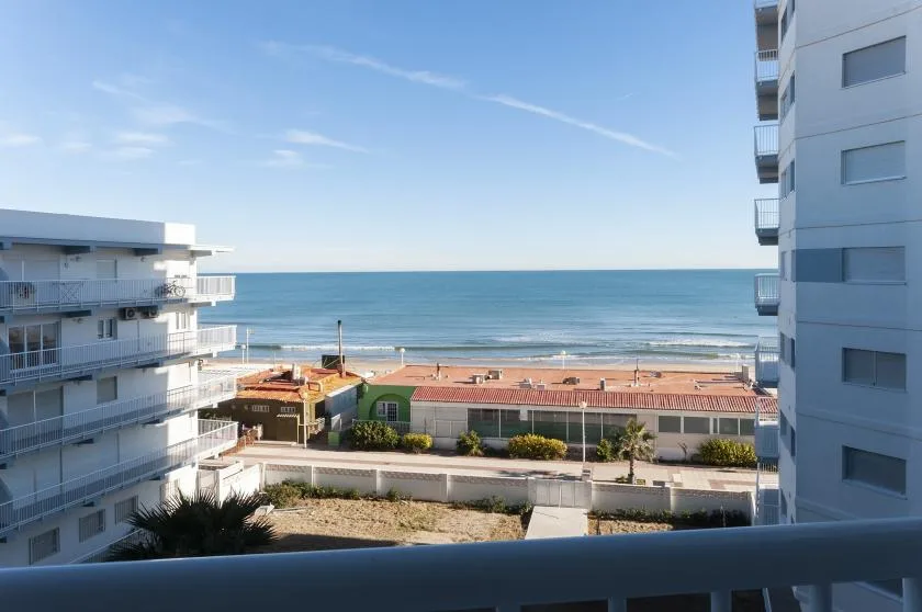 A balcony view of the sea between two apartment buildings.