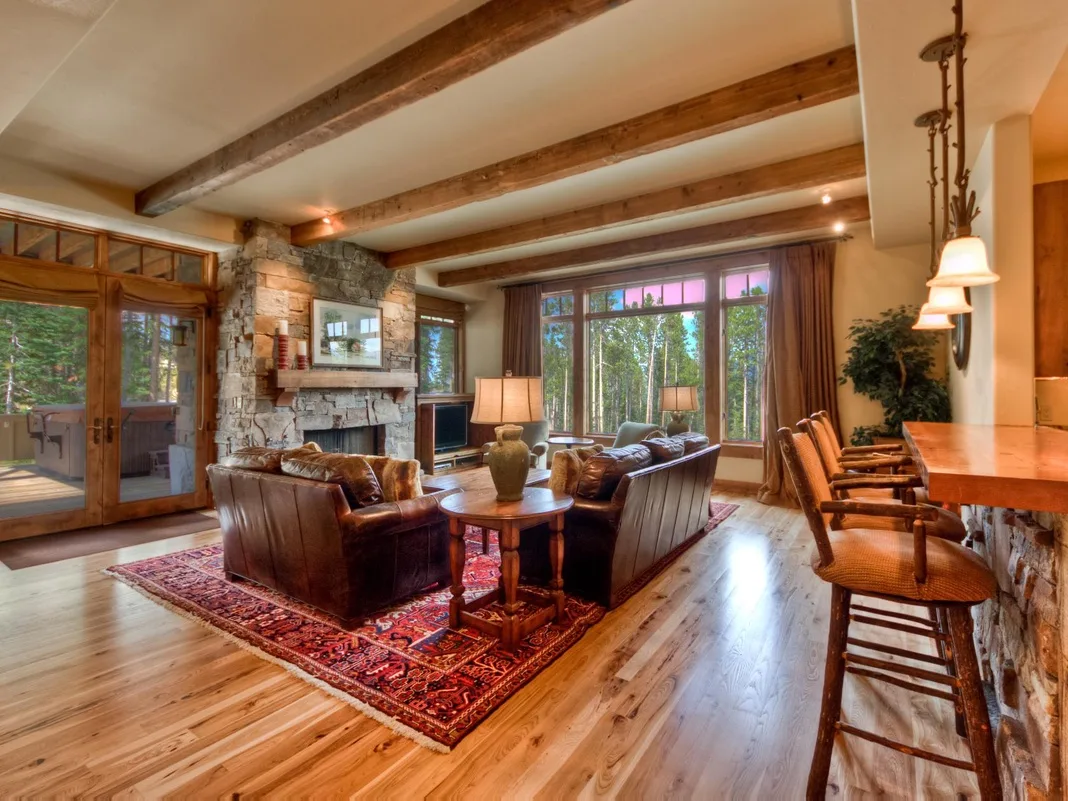 A spacious living room with seating arranged around a coffee table beside large windows.