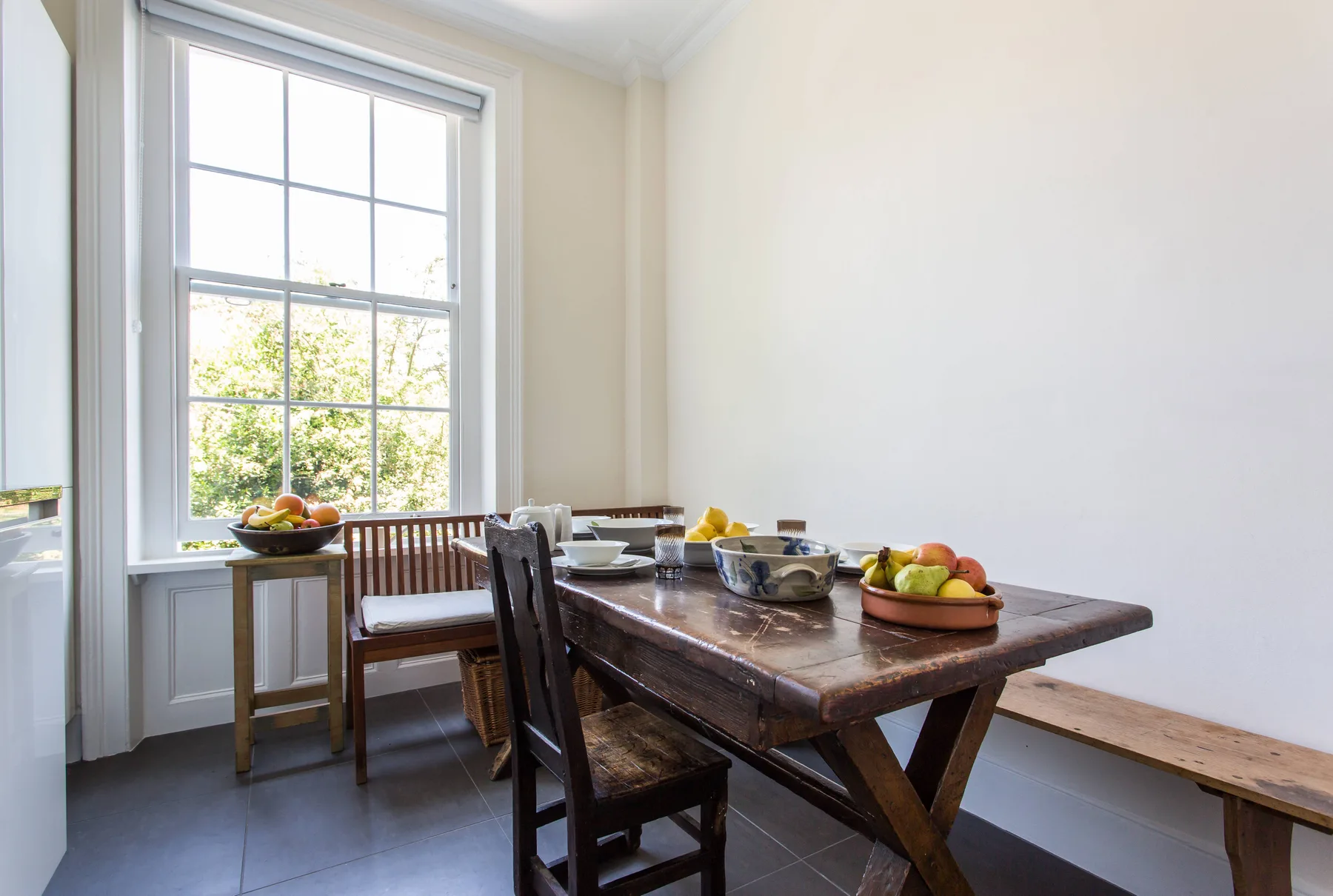 Un comedor con una mesa de madera y asientos junto a una ventana grande.