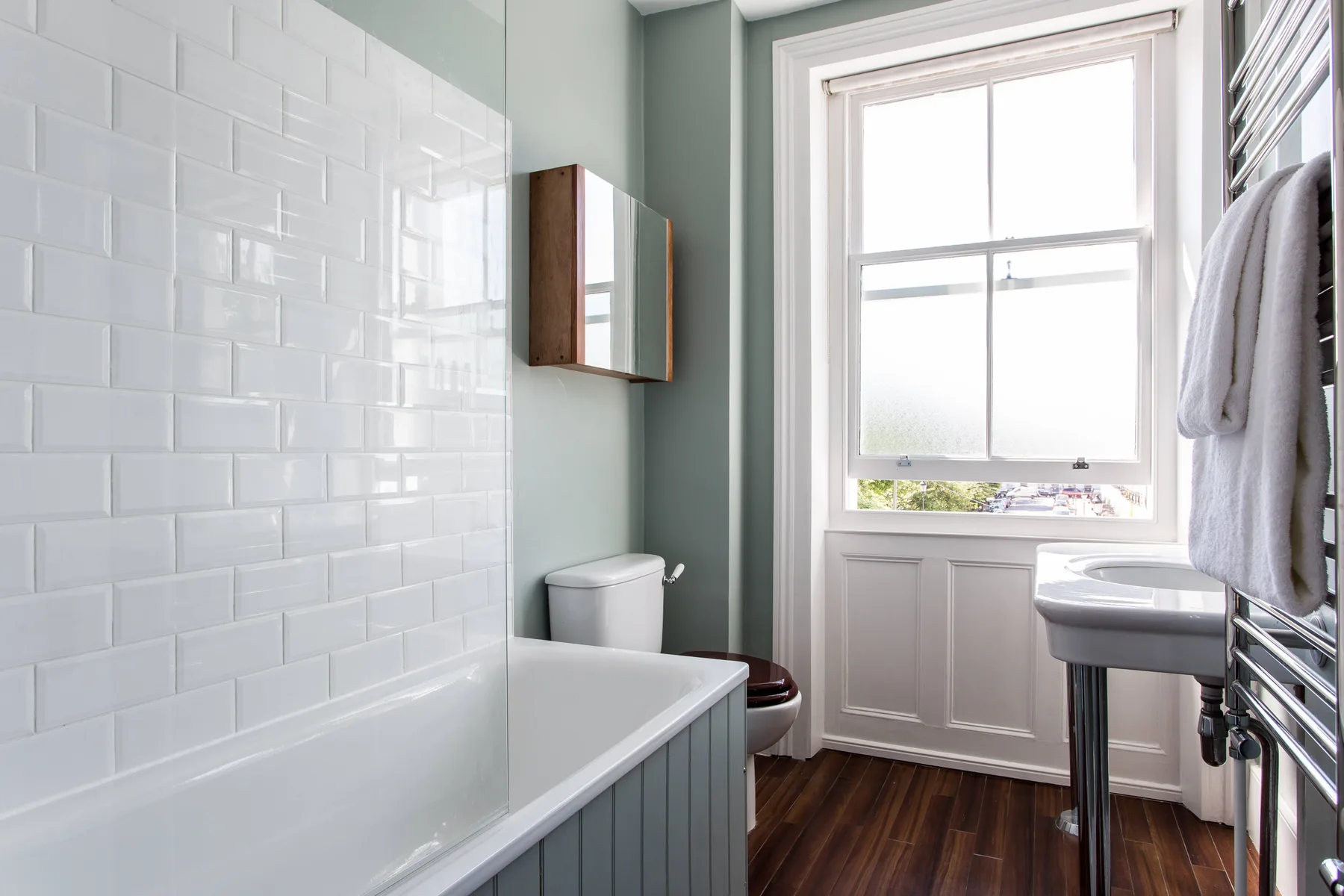 Un baño luminoso con bañera, lavabo y una ventana grande.