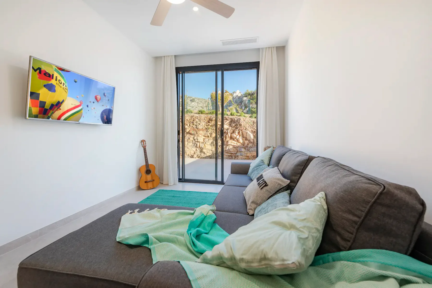 A bright living room with seating facing sliding glass doors and a garden view.