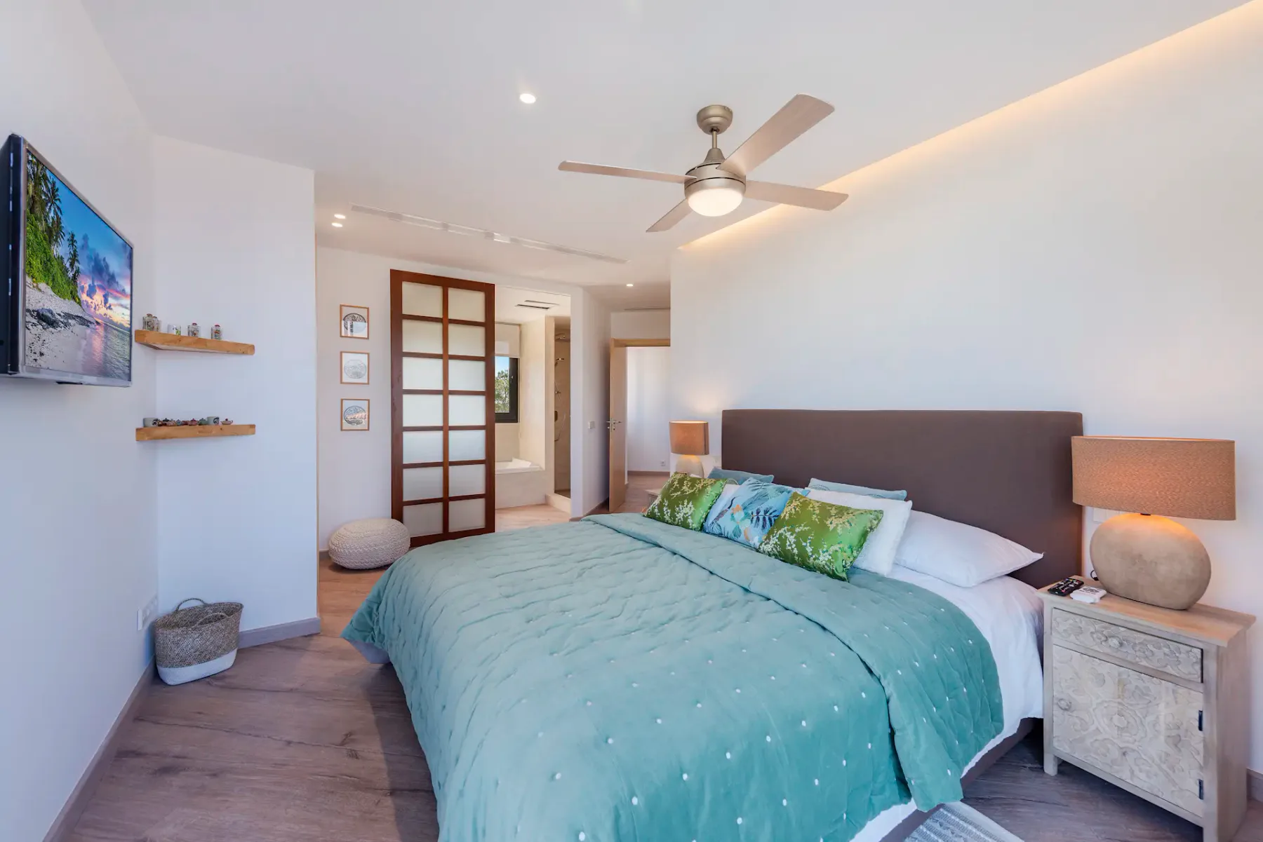 A bedroom with a bed, bedside tables, and a wall-mounted television.