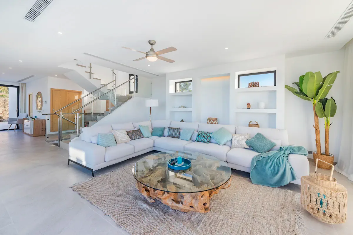 A bright living room with an L-shaped seating area and round coffee table.