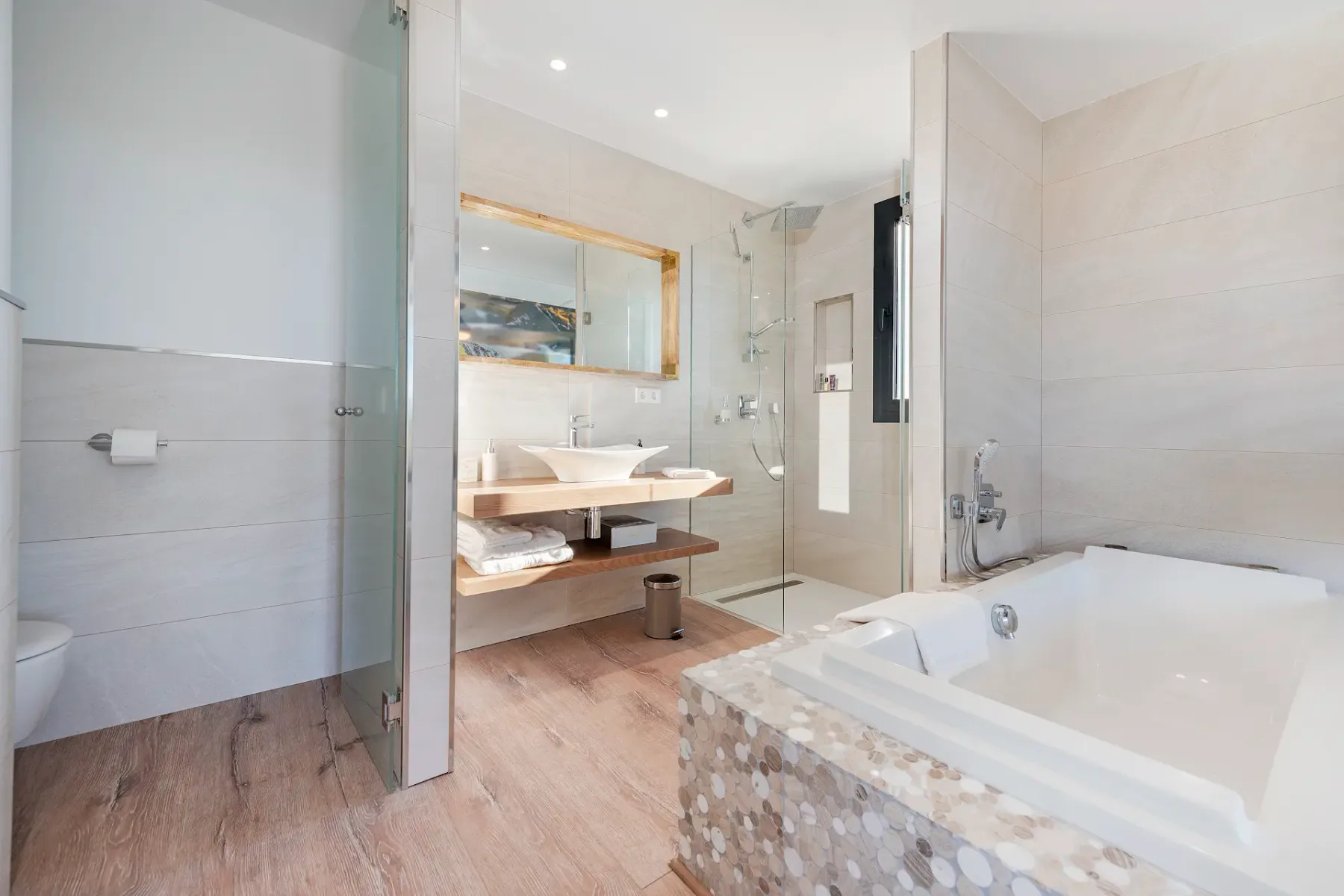 A bright bathroom with a bathtub, glass shower, and double-sink vanity.