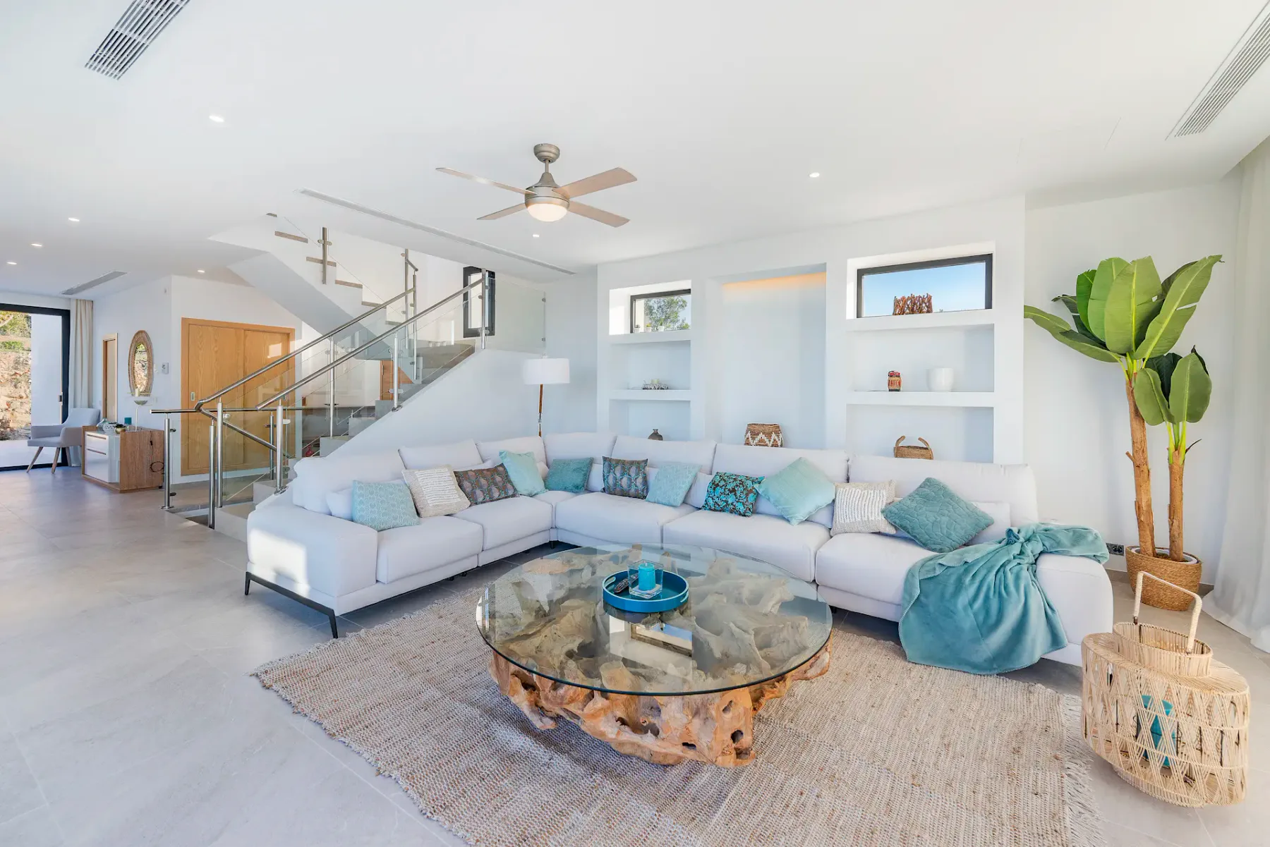 A bright living room with sectional seating and a glass coffee table.