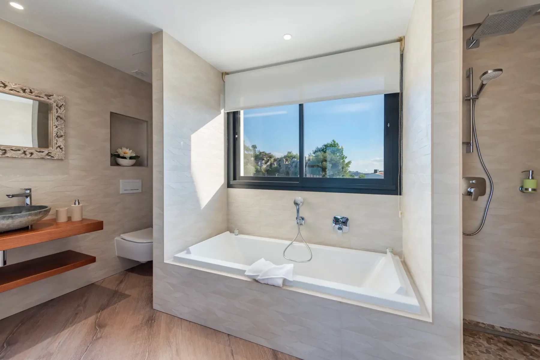 A bathroom with a bathtub beneath a large window and a separate shower.