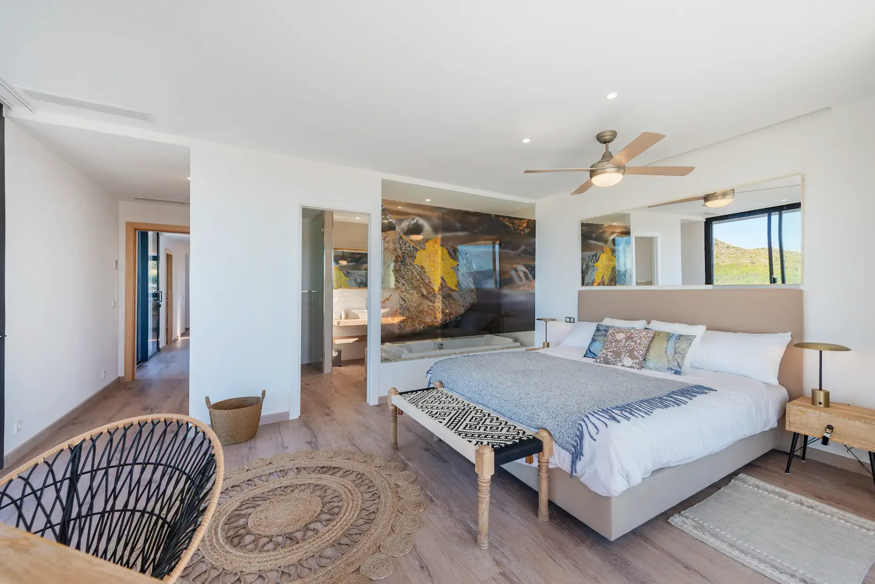A bright bedroom with a bed, ceiling fan, and windows.