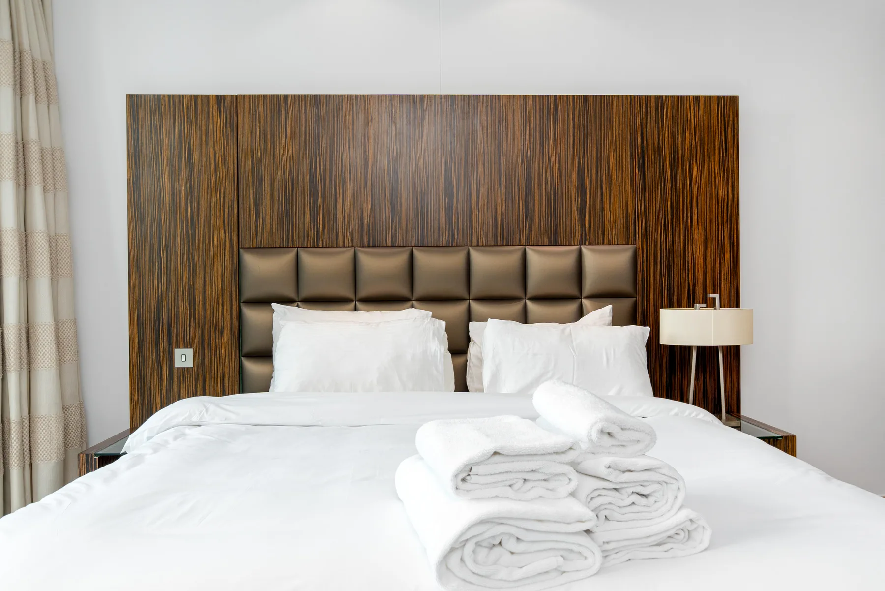 Un dormitorio con una cama tendida y toallas dobladas.