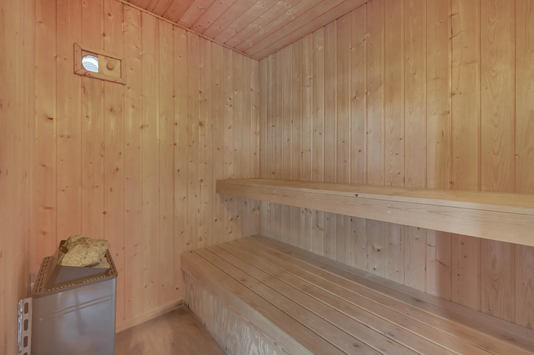 Una sauna revestida de madera con asientos de madera a distintos niveles.