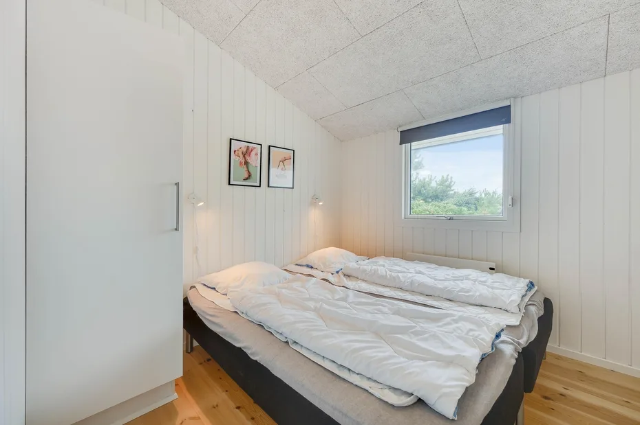 Un dormitorio con una cama deshecha junto a una ventana.
