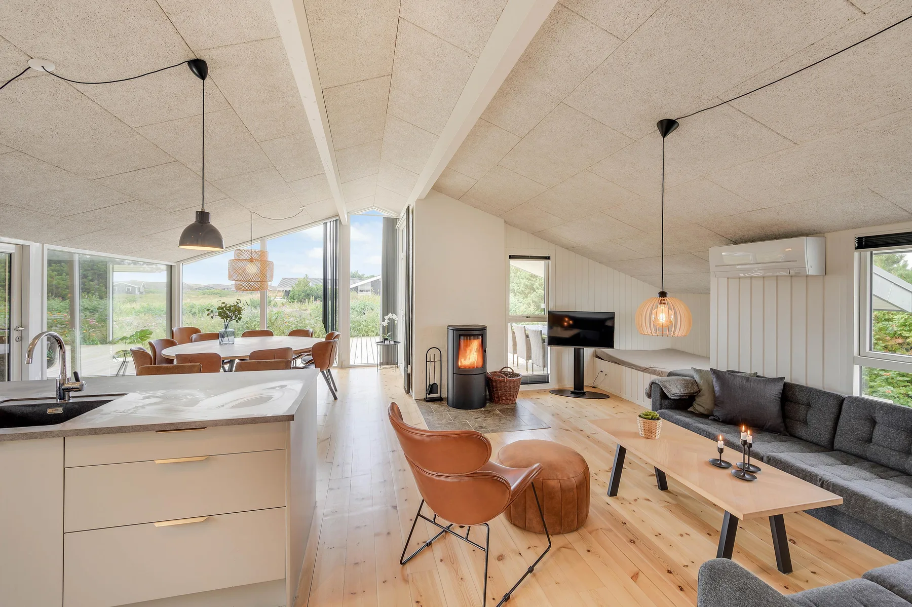 Una luminosa sala de estar y cocina diáfanas, con asientos junto a grandes ventanas.