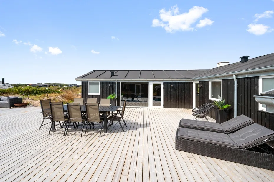 Una amplia terraza de madera con asientos al aire libre junto a una casa.