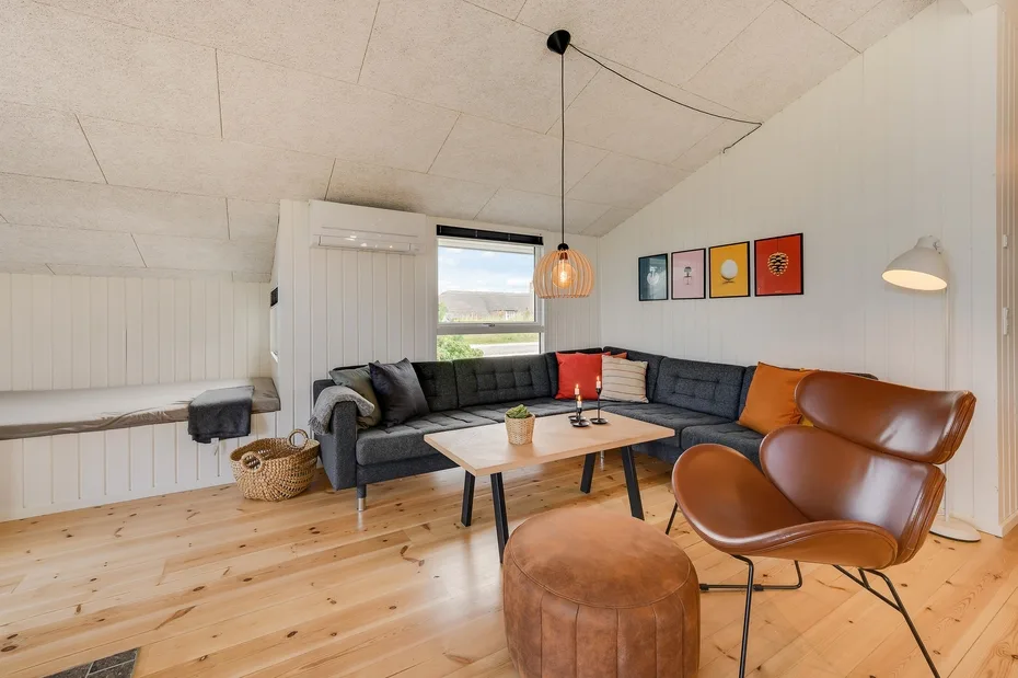 Una sala luminosa con asientos seccionales, una mesa de centro y un sillón amplio.