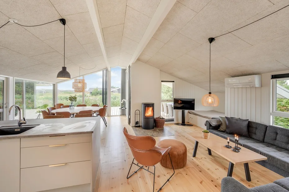 Una sala de estar y cocina de planta abierta con grandes ventanas y comedor.