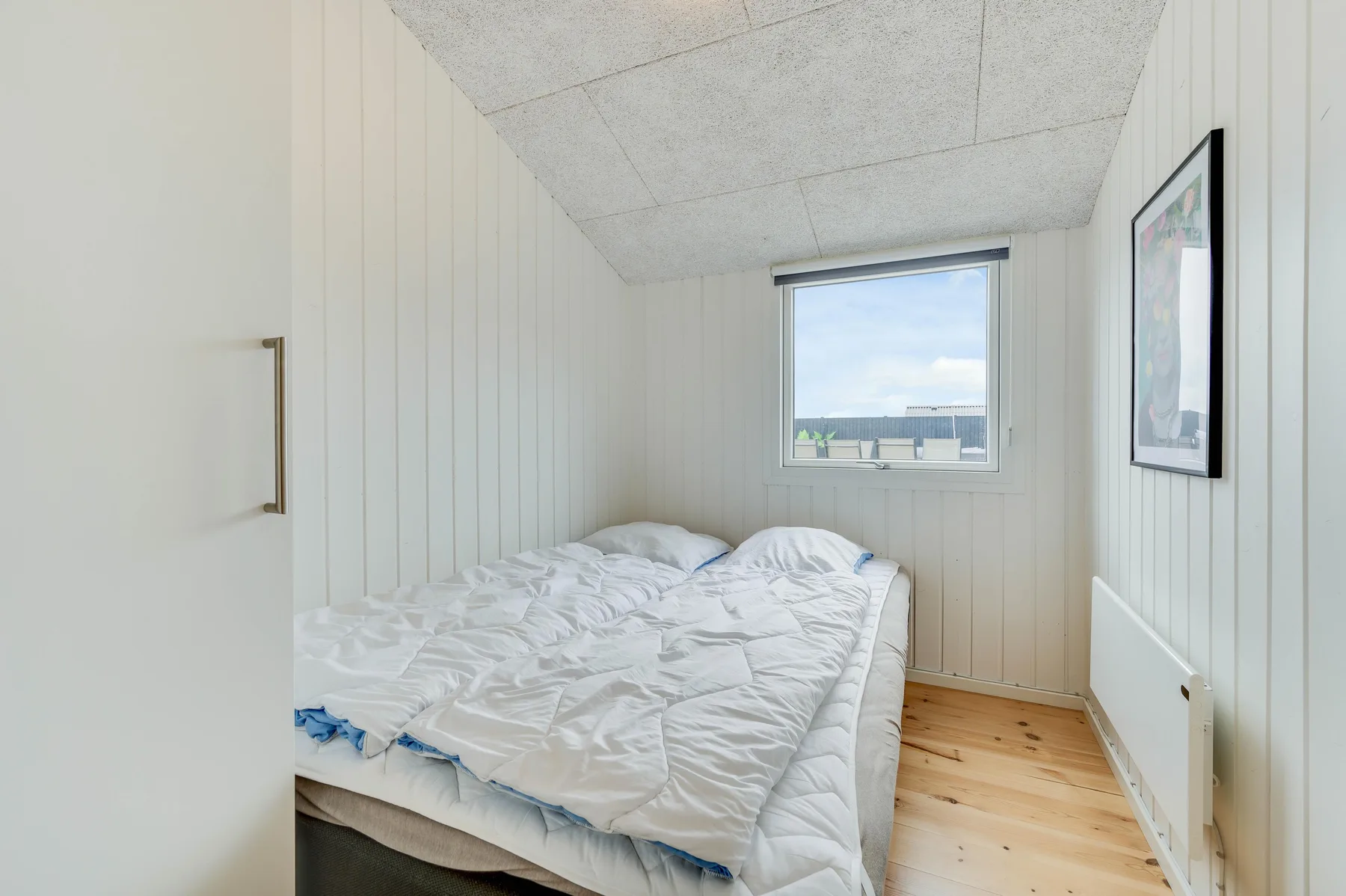 Un dormitorio pequeño con una cama bajo una ventana.
